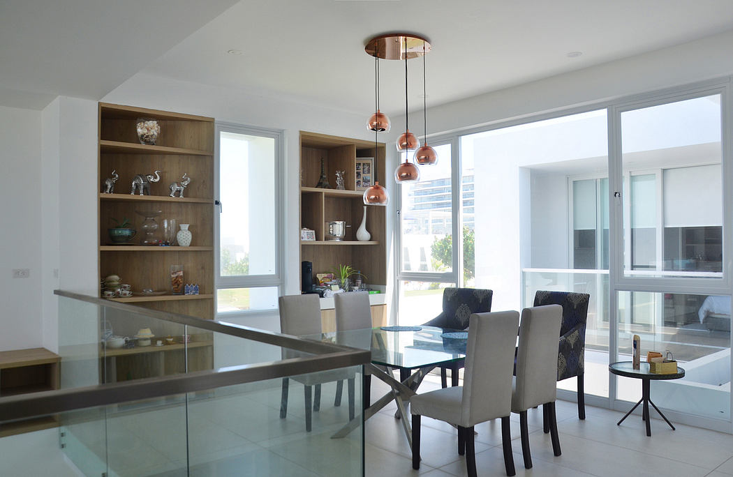 Bright, open-plan dining space with glass table and copper pendants.
