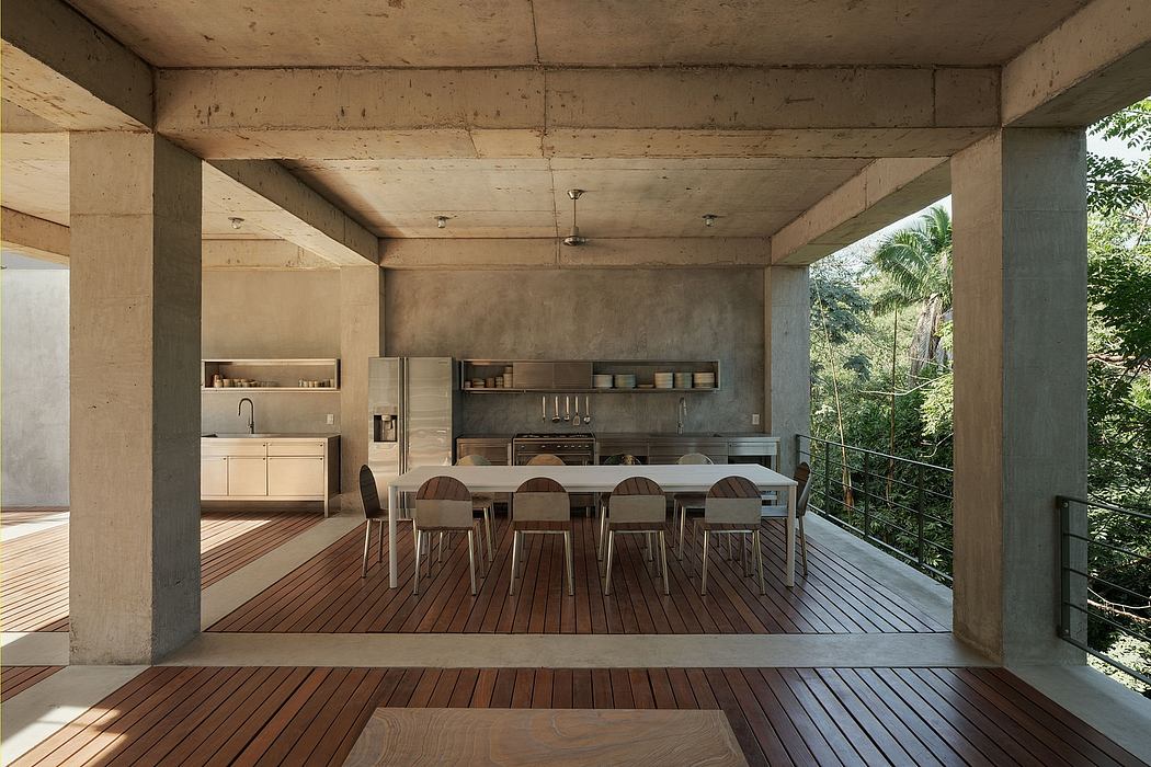 Modern kitchen with dining area in an open-plan space with concrete beams and wooden deck