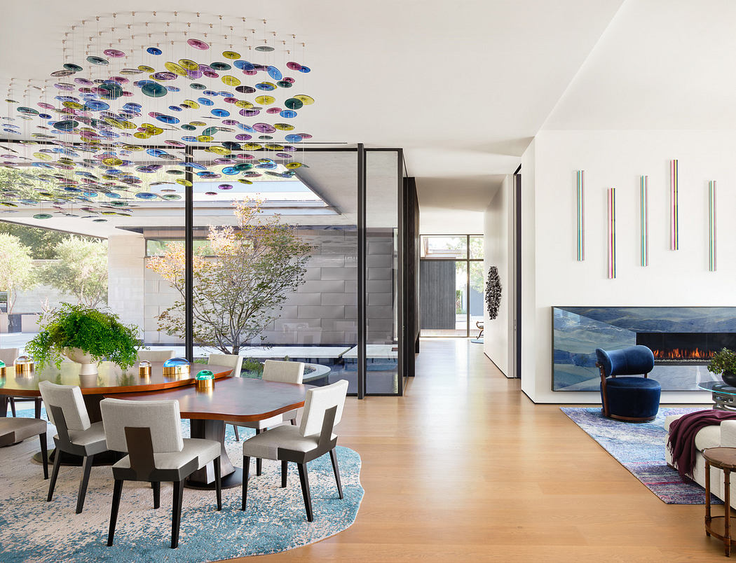 Modern dining room with colorful ceiling sculpture and fireplace.