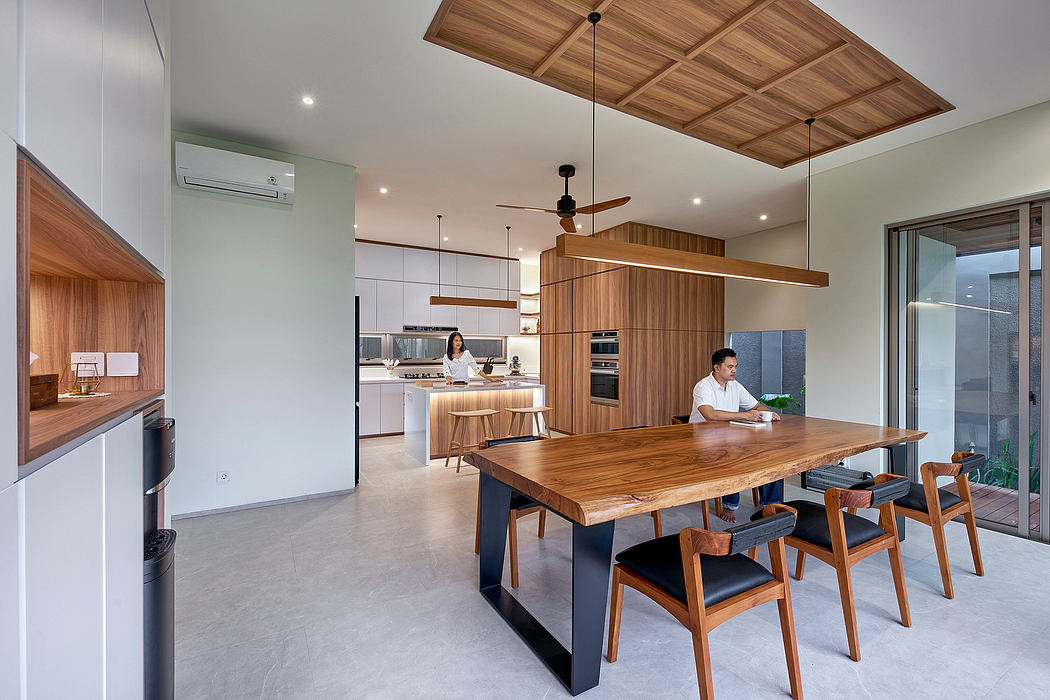 Modern kitchen interior with wooden dining table and people.