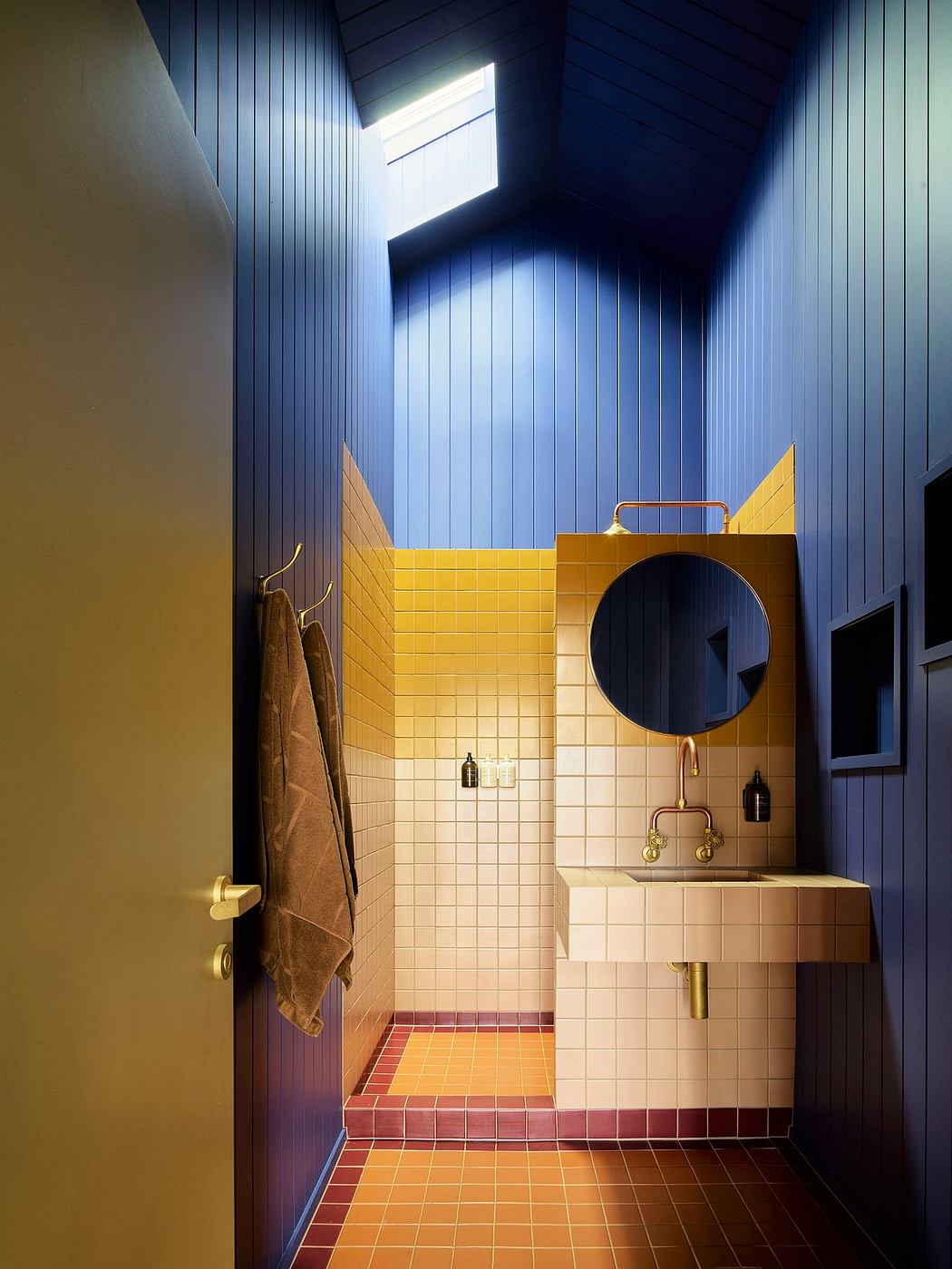 Modern bathroom with blue walls, yellow tiles, and a skylight.