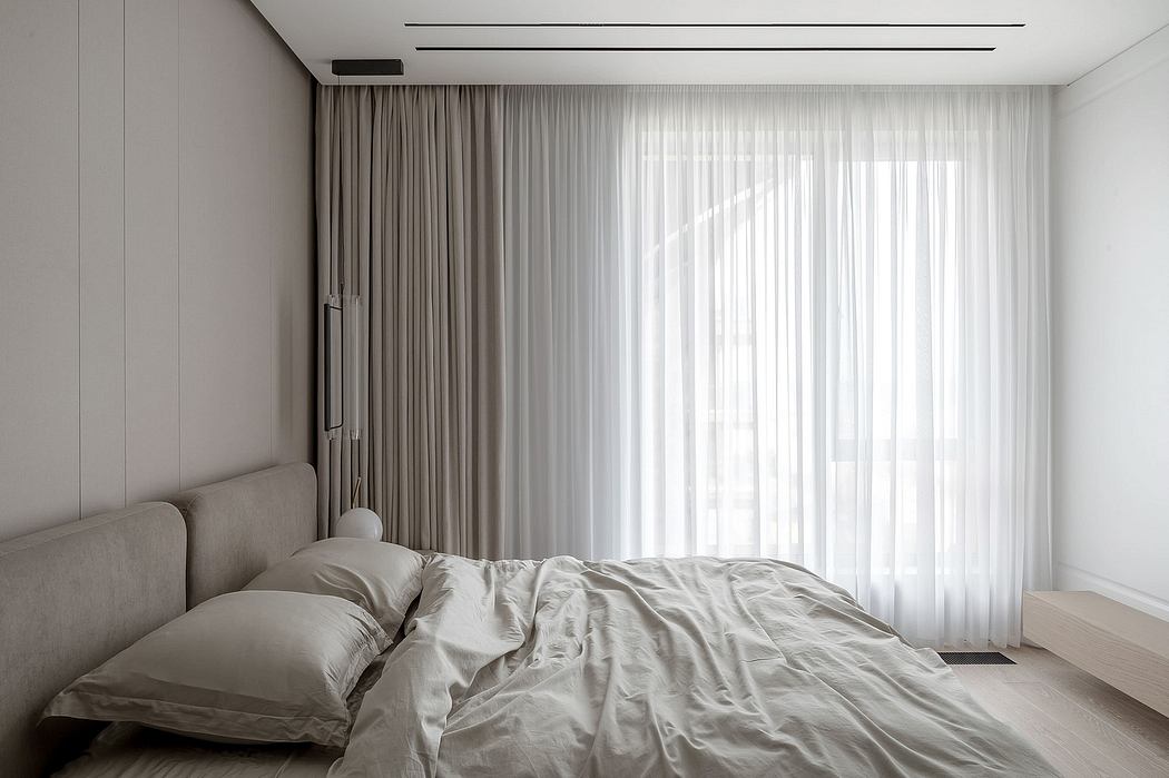 Minimalist bedroom with a bed, sheer curtains, and neutral tones.