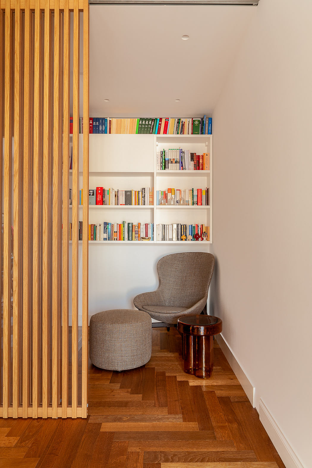 Cozy reading nook with chair, bookshelf, and wooden slats.