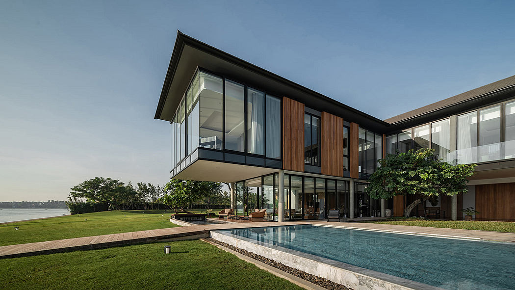 Contemporary house with large glass windows, pool, and waterfront view.
