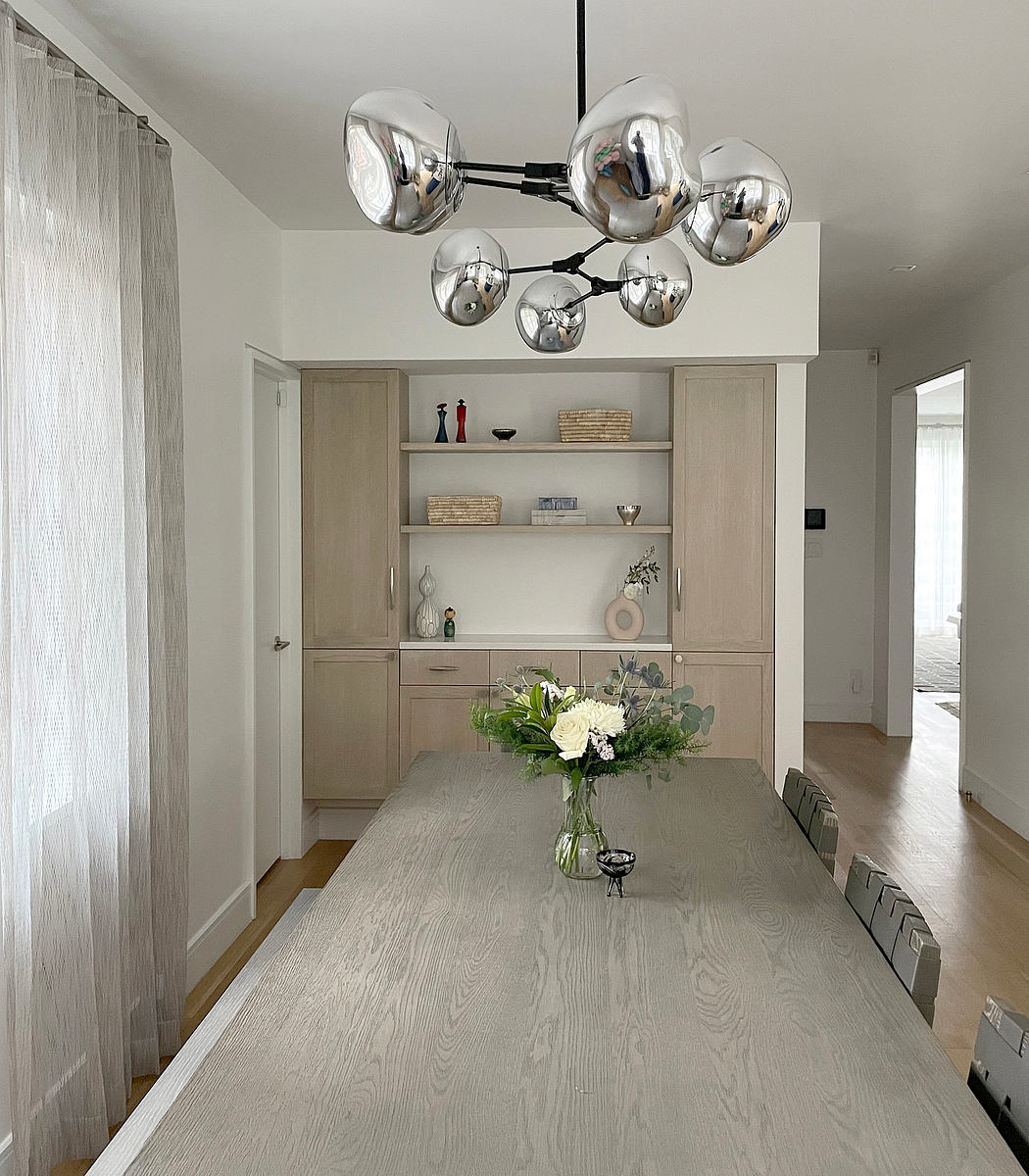 Modern dining room with a reflective spherical chandelier and wooden table.