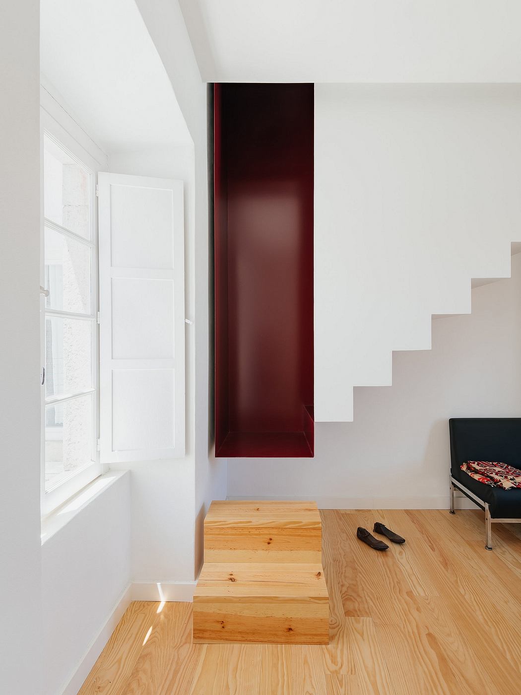 Minimalist room with white walls, wooden floors, and a tall red cabinet beside