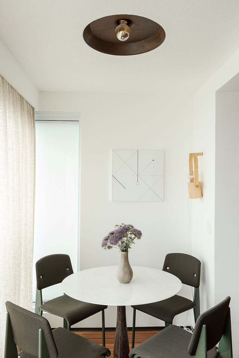 Minimalist dining area with round table, chairs, and modern lighting.