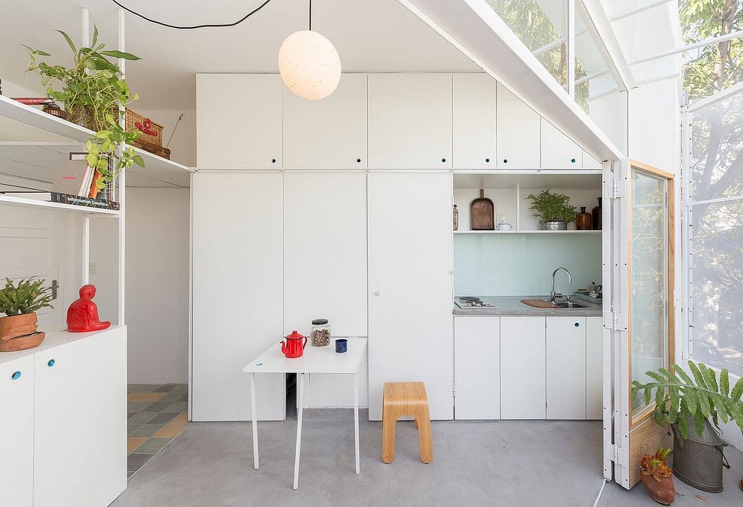 Bright minimalist kitchen with white cabinetry, a dining table, and plants.