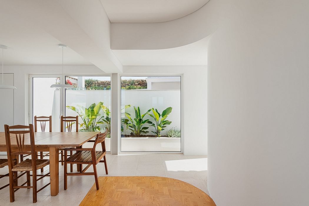 Minimalist dining space with curved walls and garden view.