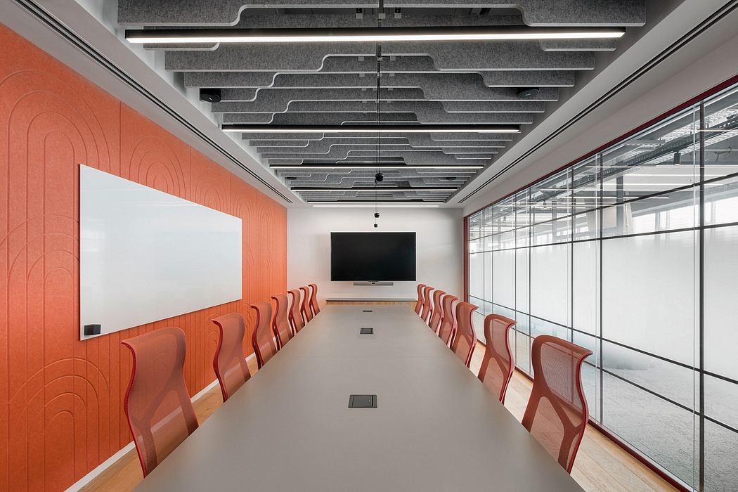 Contemporary conference room with red chairs and a patterned orange wall.