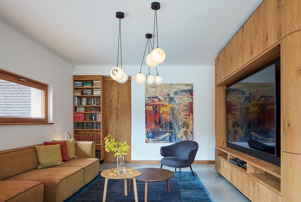 Modern living room with wooden bookshelf, pendant lights, and abstract art.