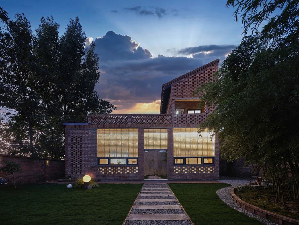 Modern brick house with patterned facade at dusk, landscape garden in front.
