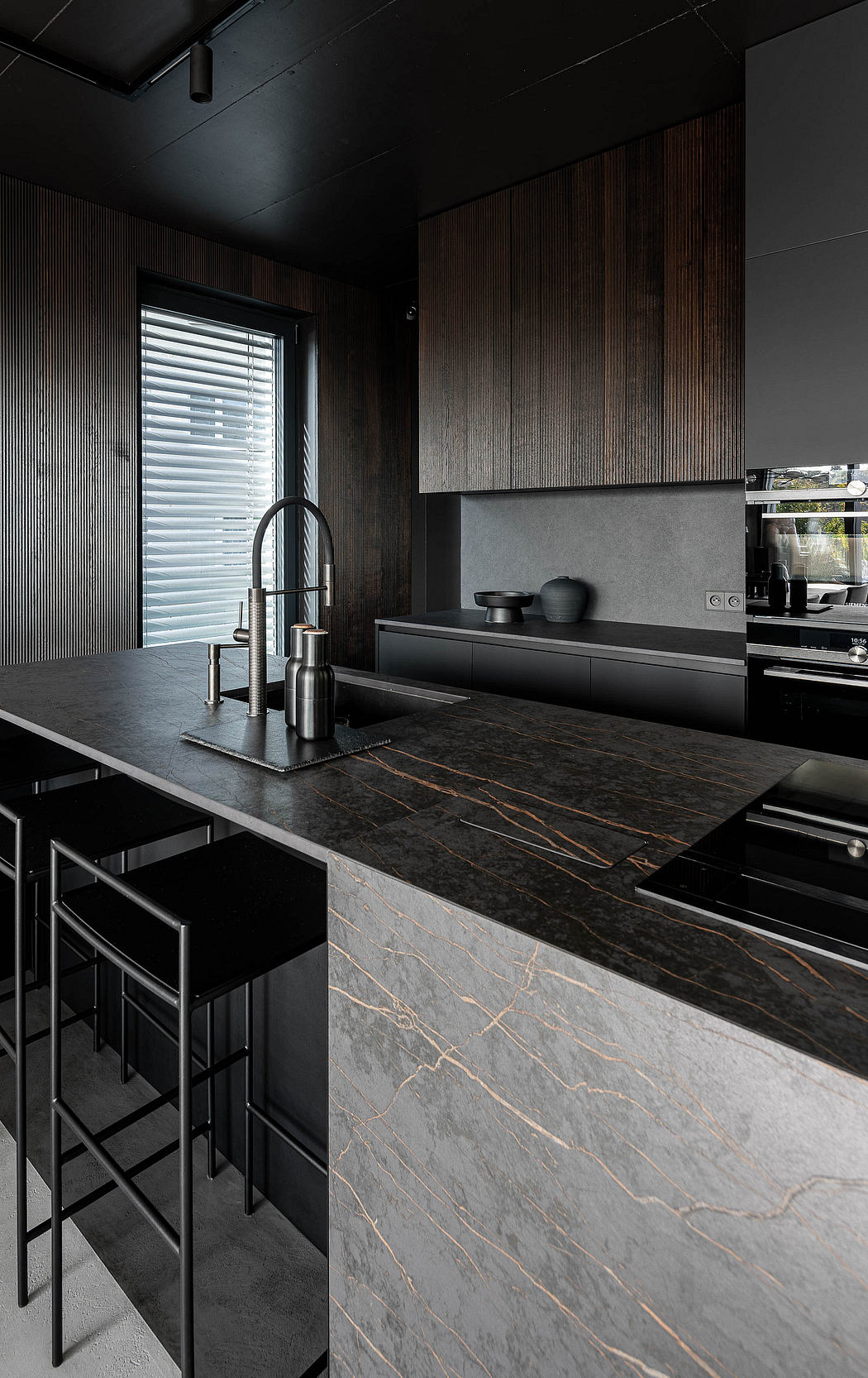 Modern kitchen with dark wood cabinets and black marble countertop.
