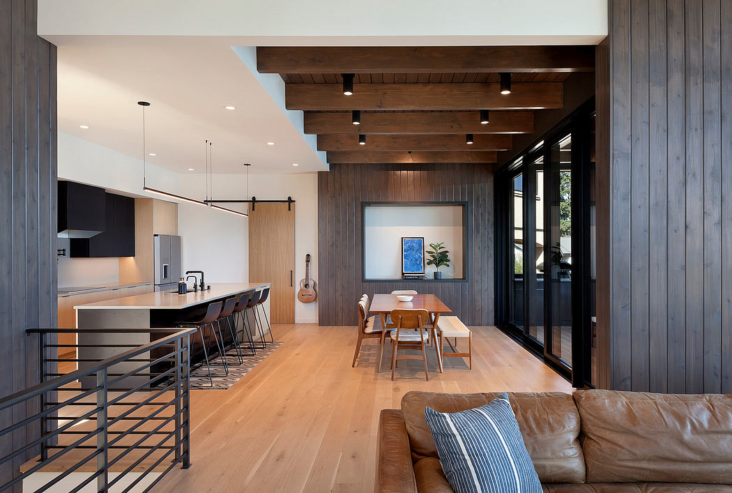 Modern kitchen with wooden design, dining area, and leather sofa.