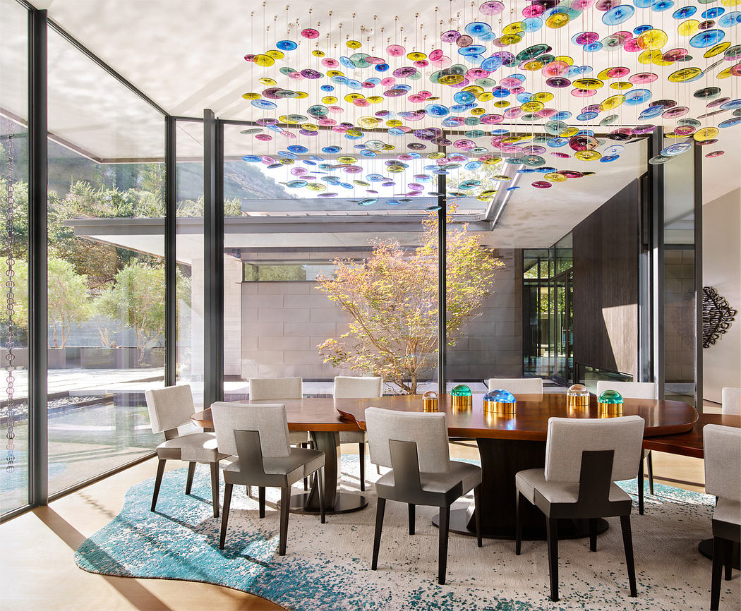 Modern dining room with colorful ceiling installation and glass walls.
