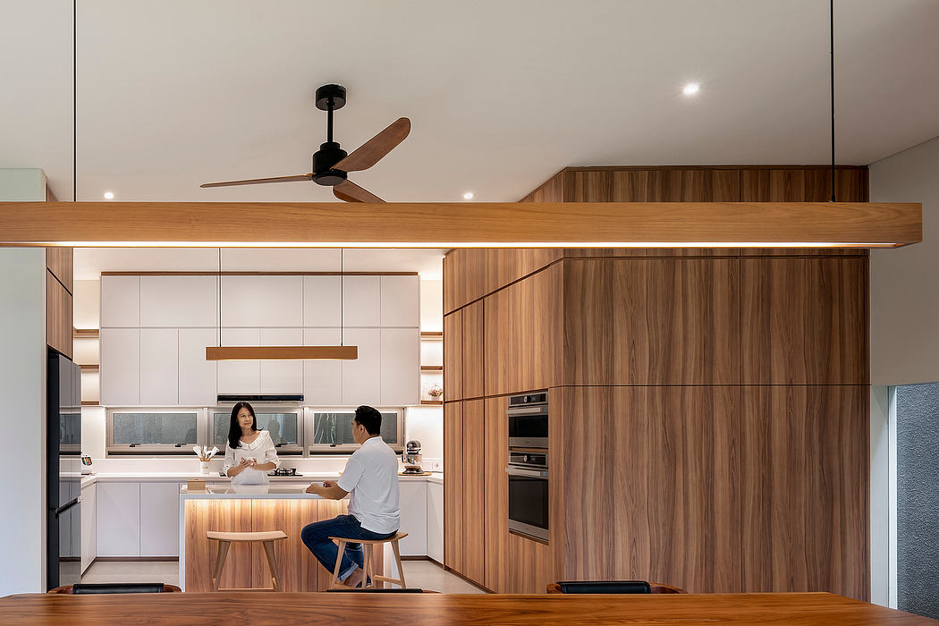 Contemporary kitchen with wood finishes and two people.