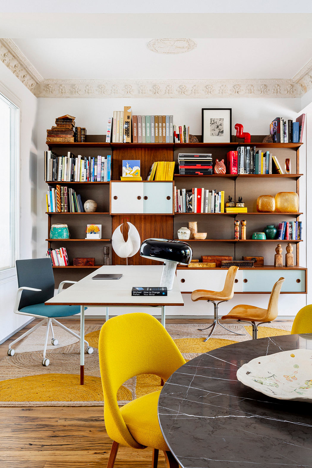 Contemporary home office with vibrant chairs and a bookshelf.