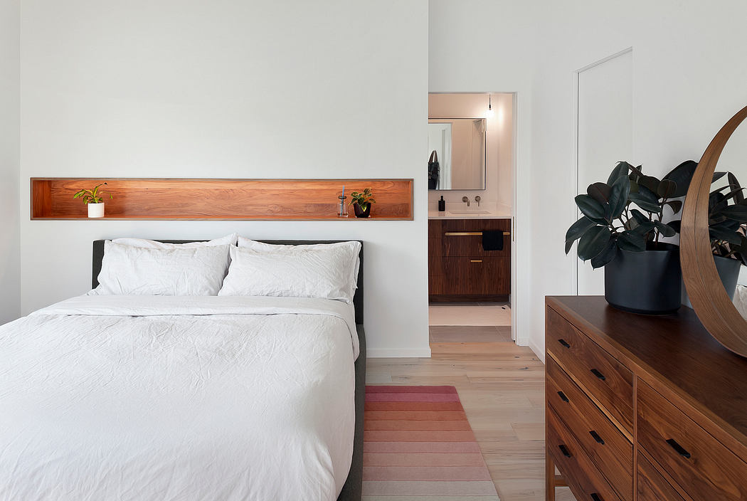 Minimalist bedroom with wooden accents and a white bed.