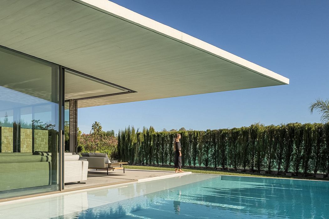 Modern house with large overhang, glass walls, and pool, with a person