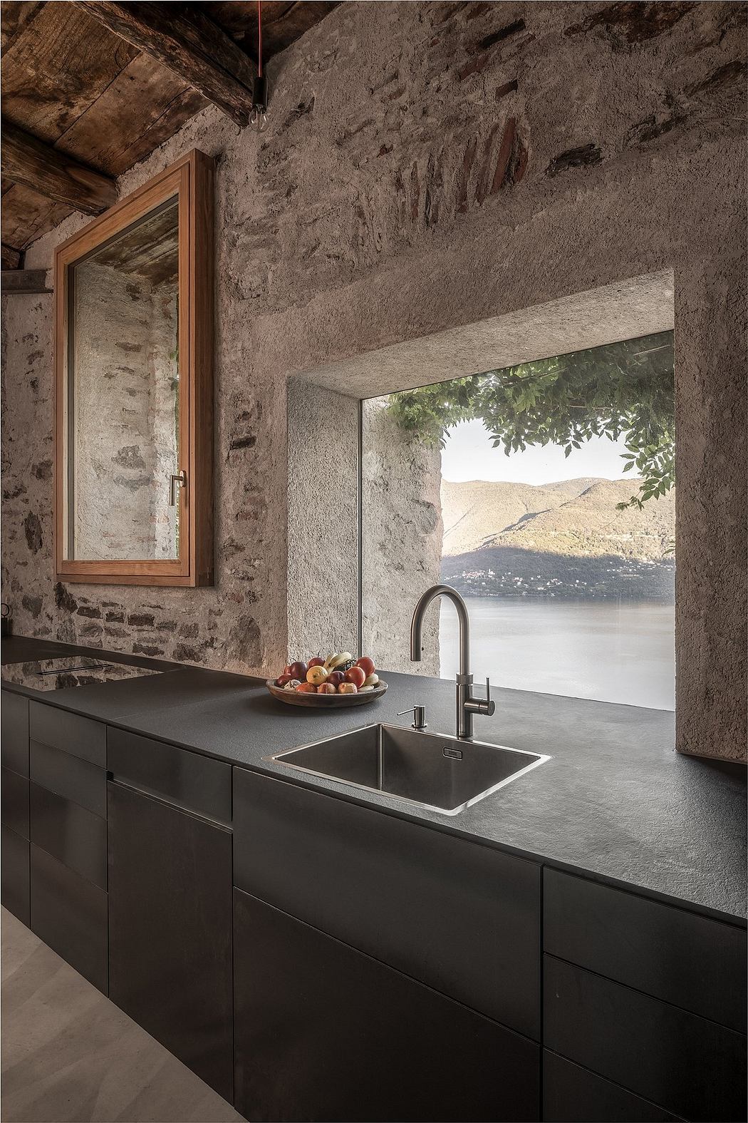 Sleek kitchen with black countertops and a window overlooking a serene lake.