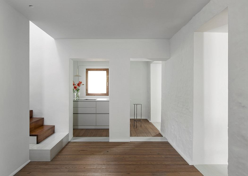 Minimalist interior with white walls, wooden floors, and a small staircase.