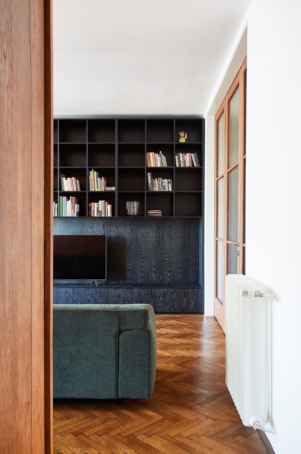 Contemporary room with a black bookshelf, herringbone floor, and a
