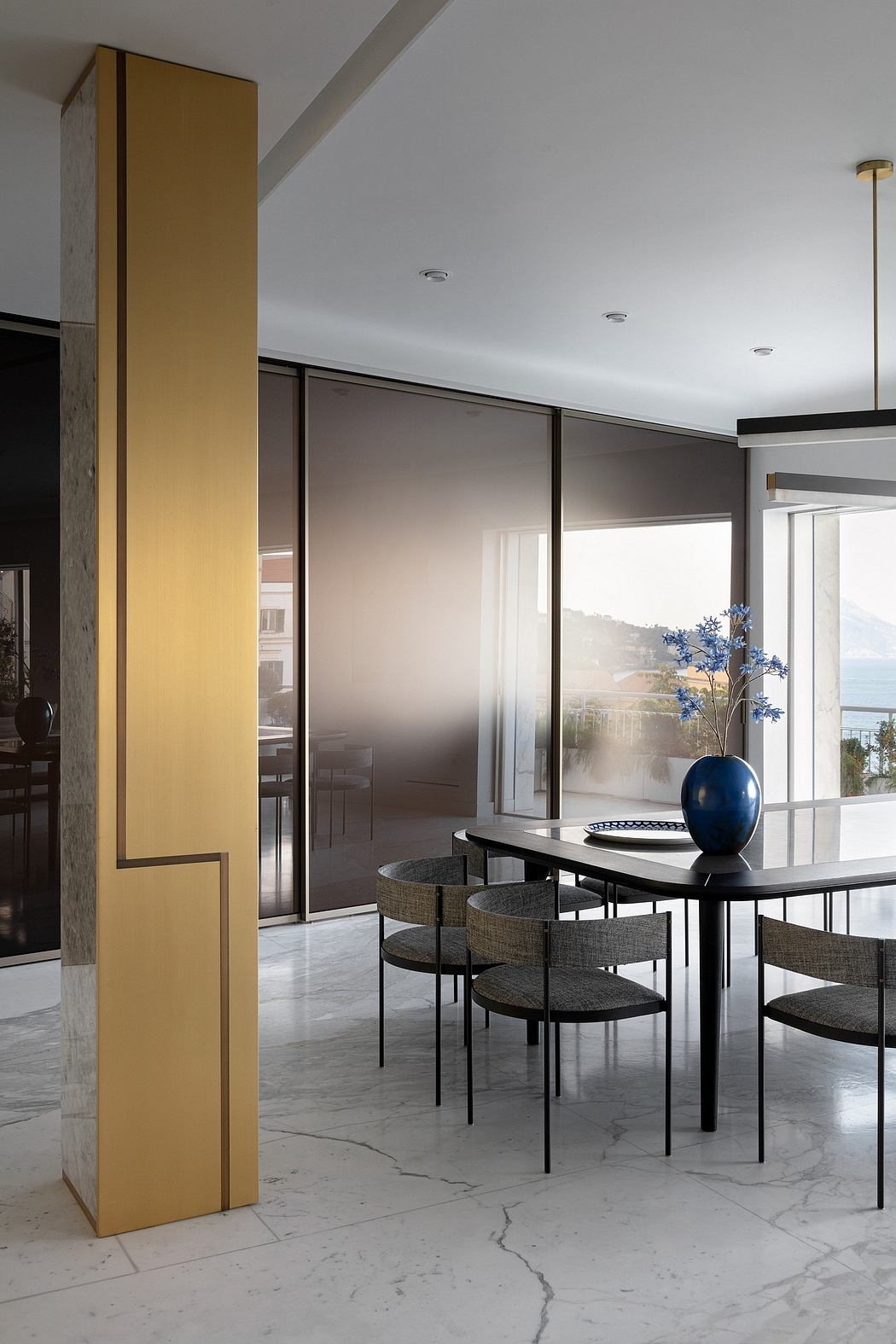Modern dining room with marble floor, glass table, and a view of the outdoors