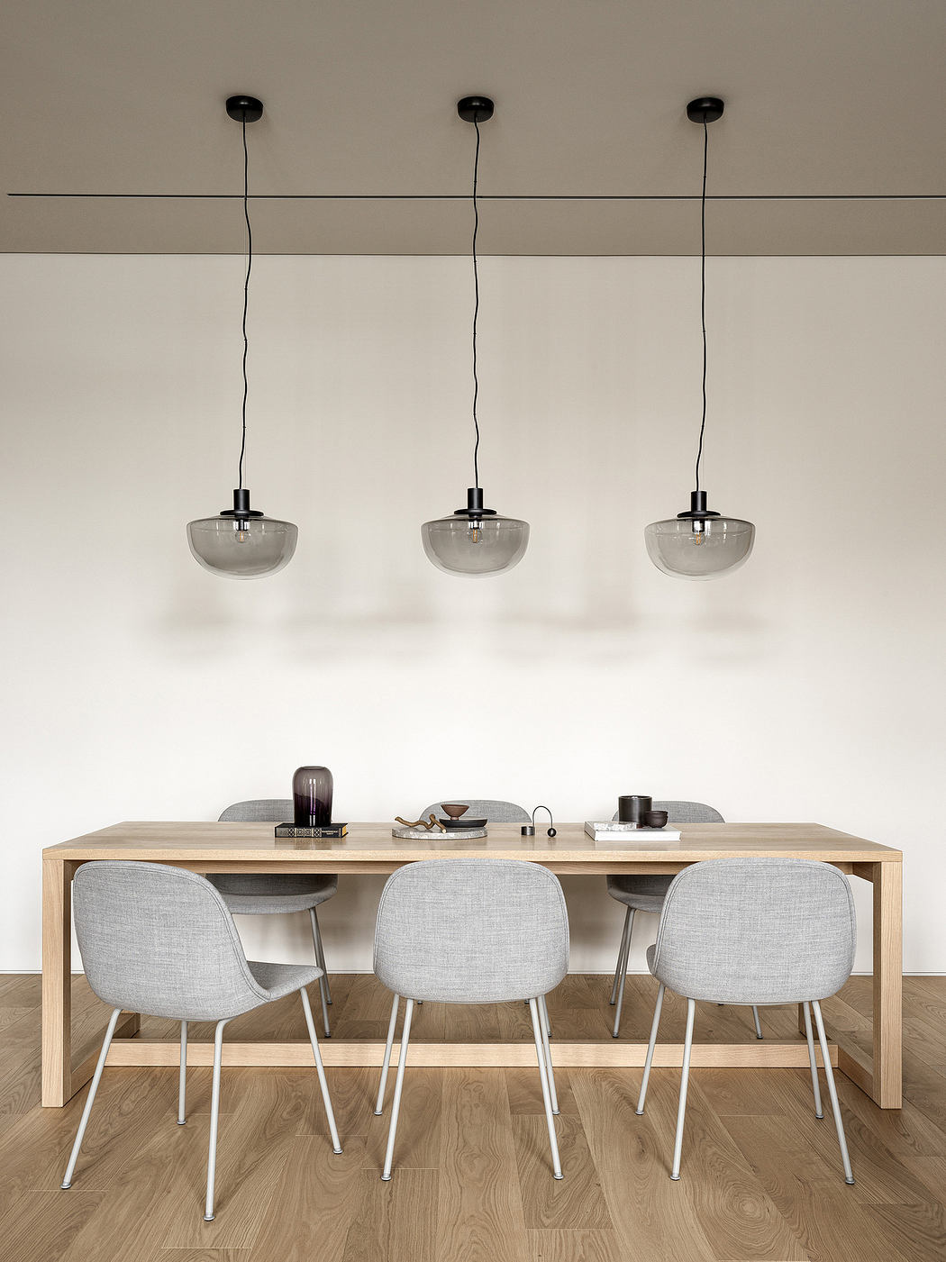 Modern dining area with a wooden table, four chairs, and three pendant lights.