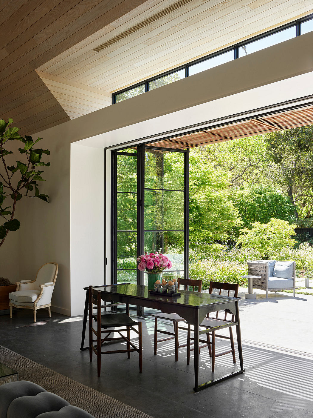 Modern dining room with large windows overlooking a garden.