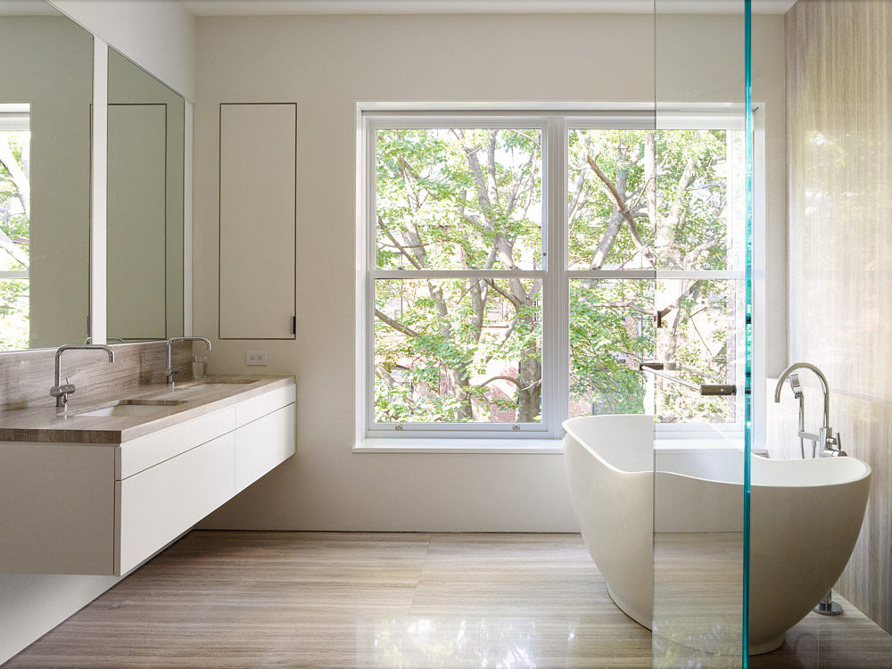 Modern bathroom with a glass partition, featuring a bathtub and sink with a view of
