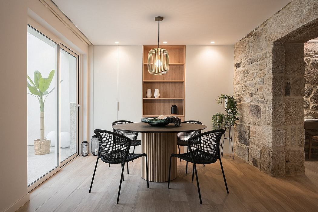Modern dining room with stone wall, wooden table, black chairs, and pendant light