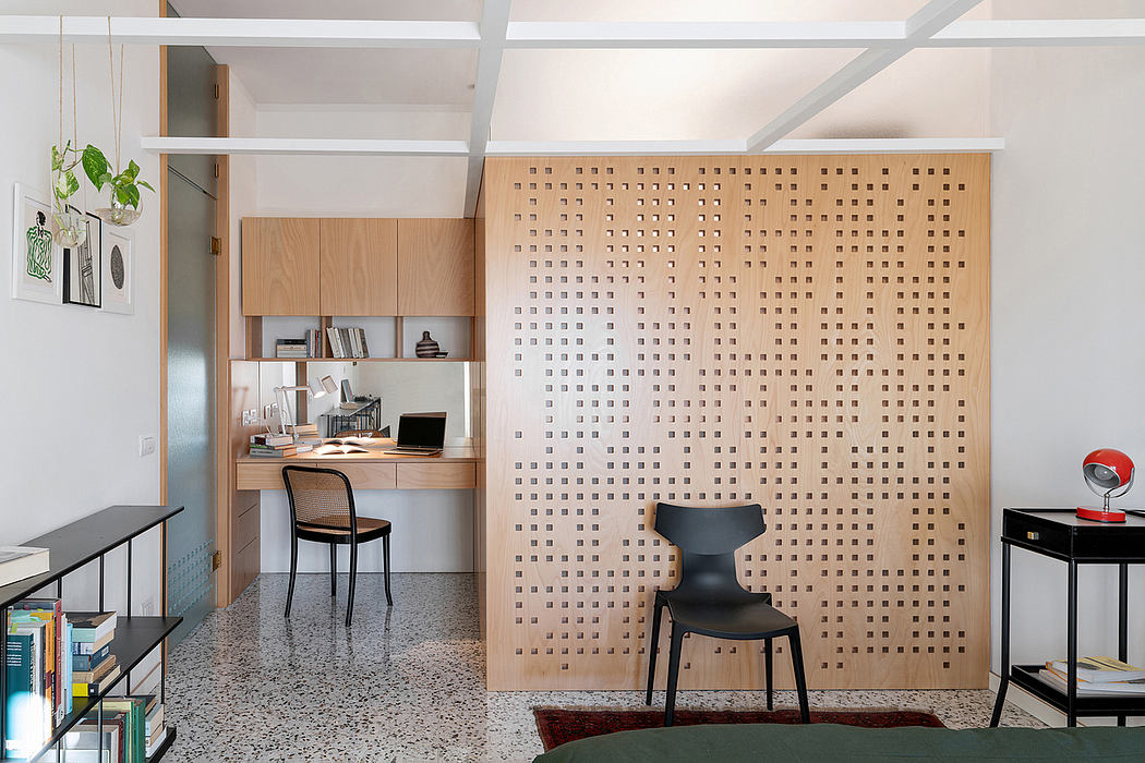 Modern interior with perforated divider panel, wooden kitchenette, and minimalist furniture.