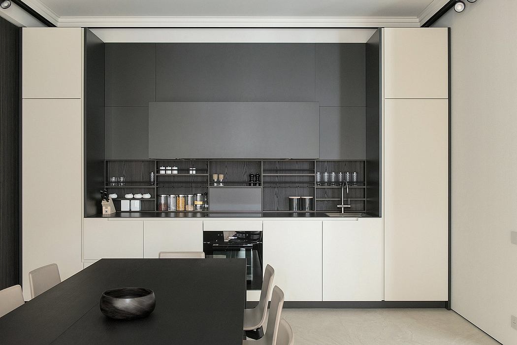 Modern kitchen with black and white cabinetry and a central dining table.