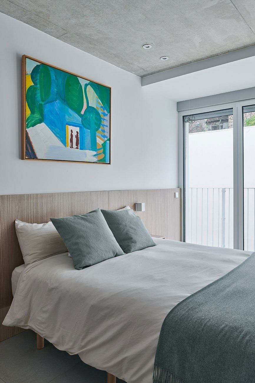 Minimalist bedroom with a large abstract painting above the bed.