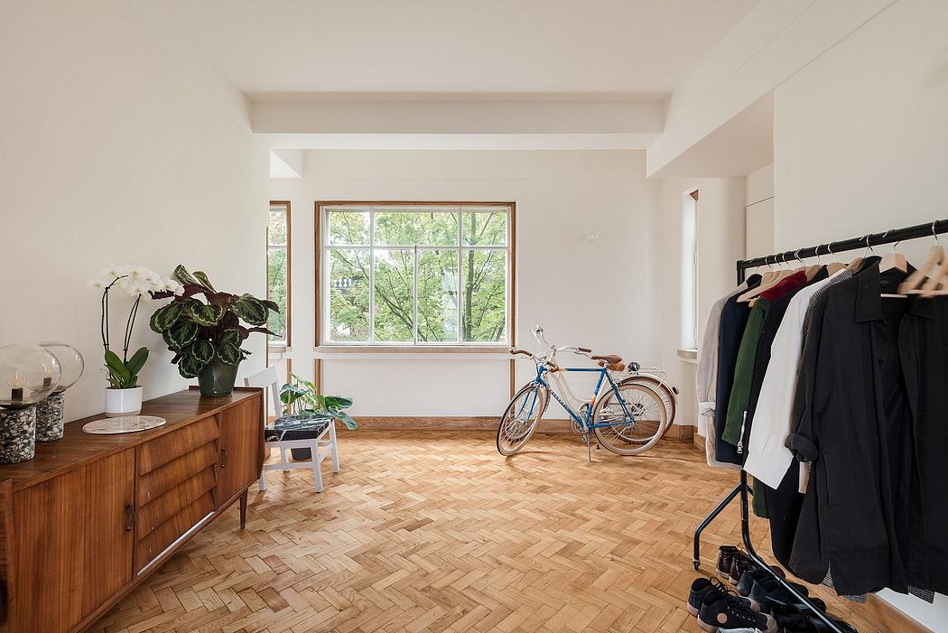 Bright minimalist room with large window, clothing rack, bicycle, and wooden herring