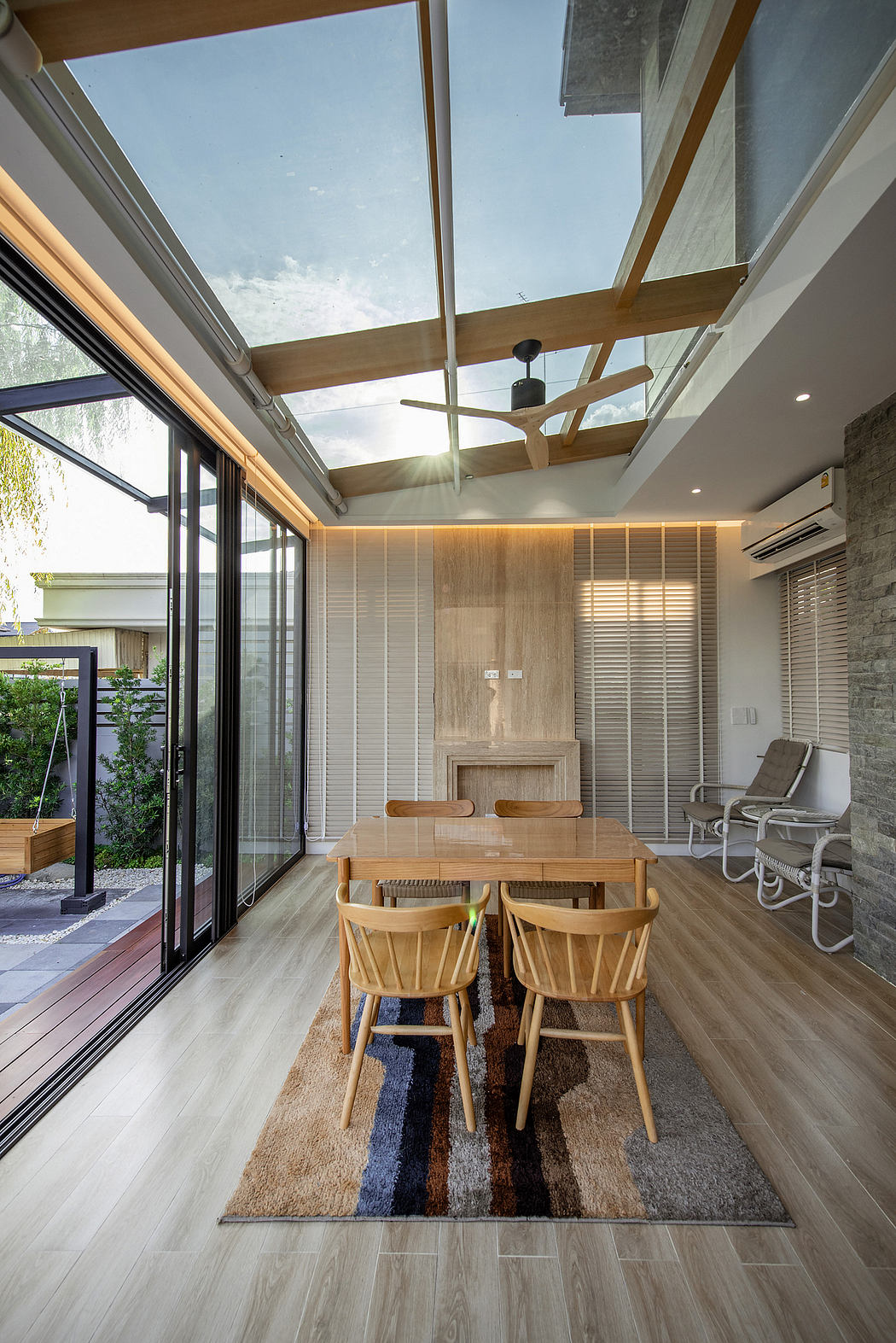 Modern dining room with glass ceiling and wooden furniture.