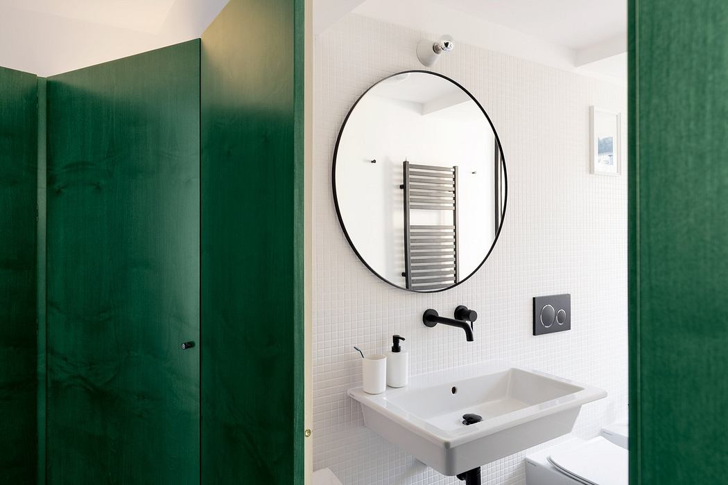 Contemporary bathroom with white tiles, round mirror, and green door.