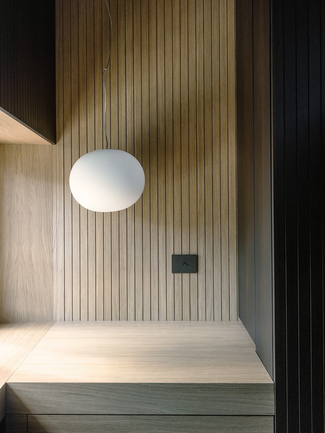 Wood-paneled corner with a simple white pendant light.