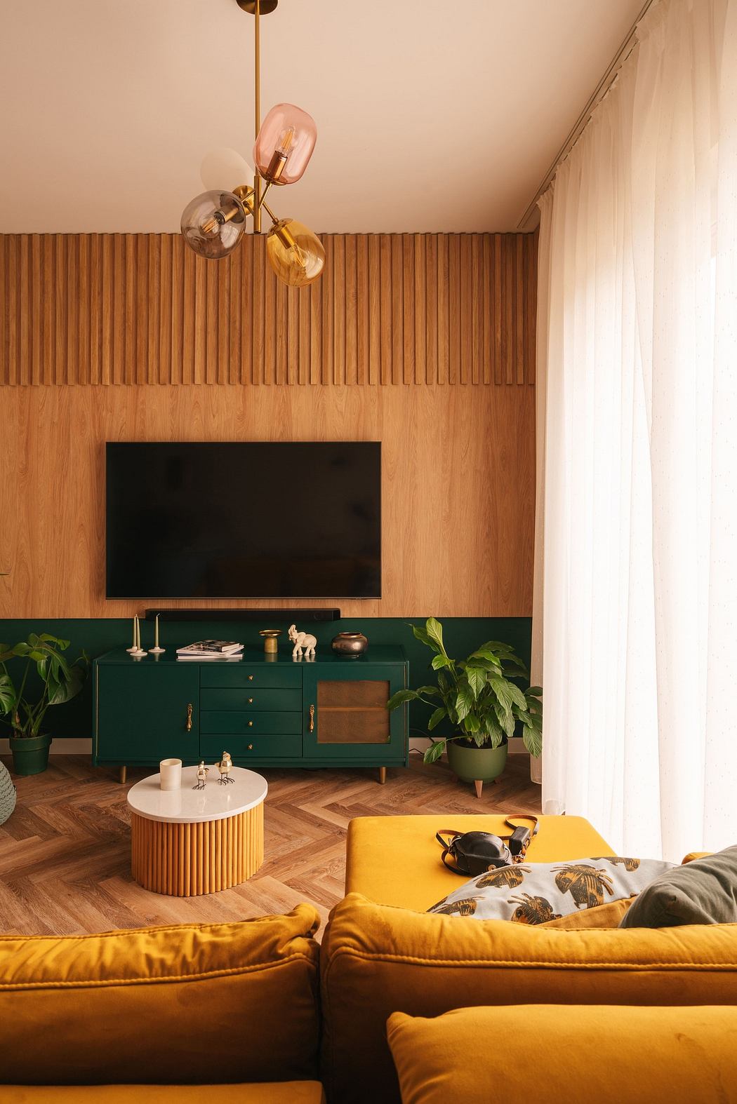 Modern living room with mustard sofa, green cabinet, and wood paneling.