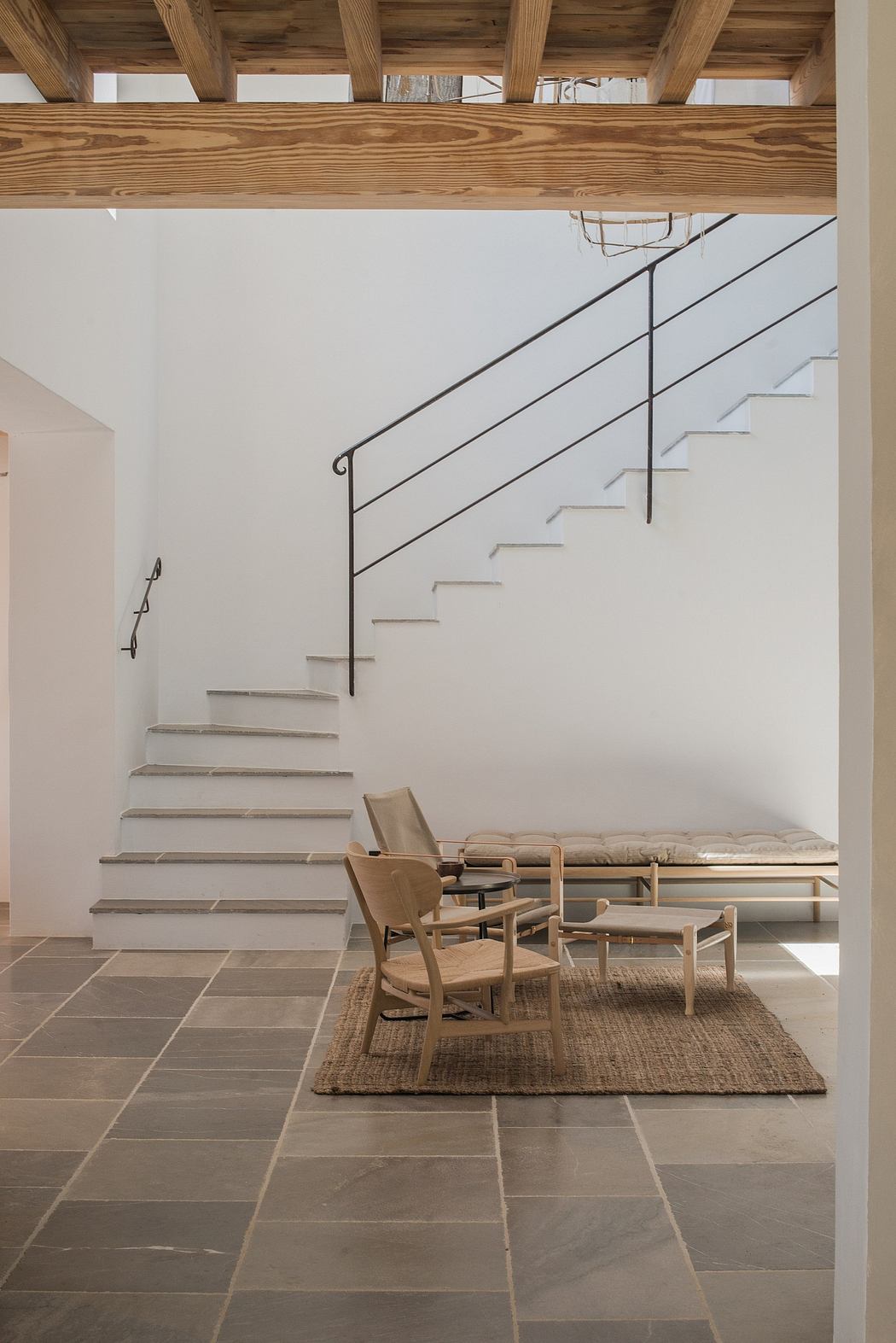 Minimalist interior with stairs, wooden beams, and simple furniture.
