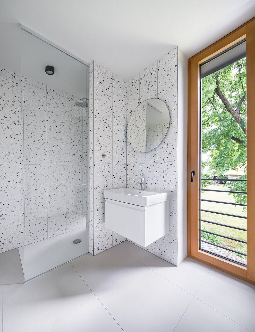 Minimalist bathroom with terrazzo walls and a large window.
