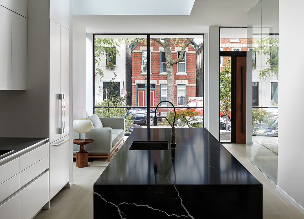 Modern kitchen with marble island leading to a living area with large windows.