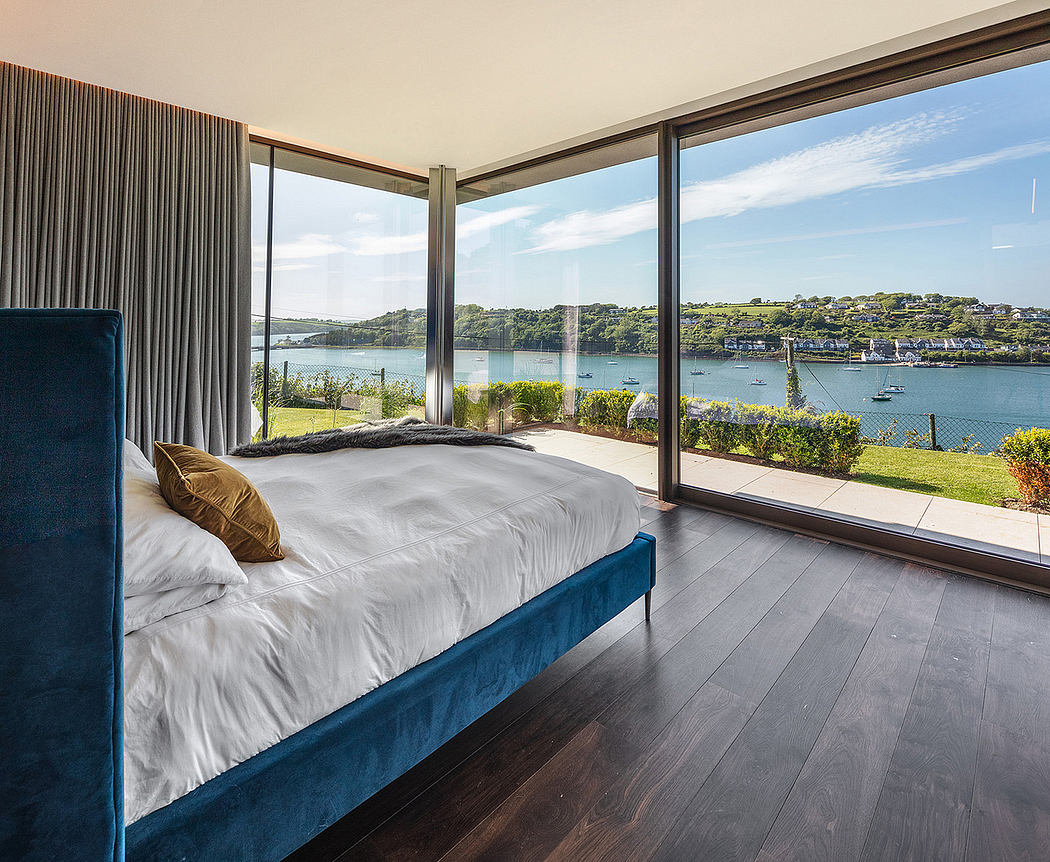 Bedroom with panoramic water view and floor-to-ceiling windows.