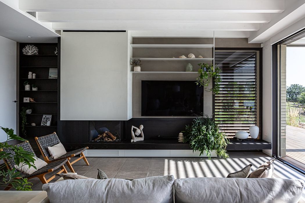 Modern living room with a TV, bookshelves, plants, and sliding door