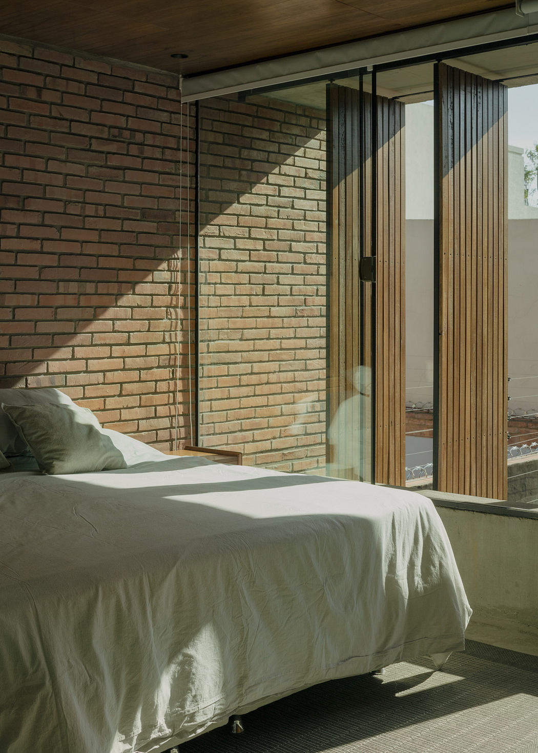 Contemporary bedroom with brick wall and floor-to-ceiling windows.