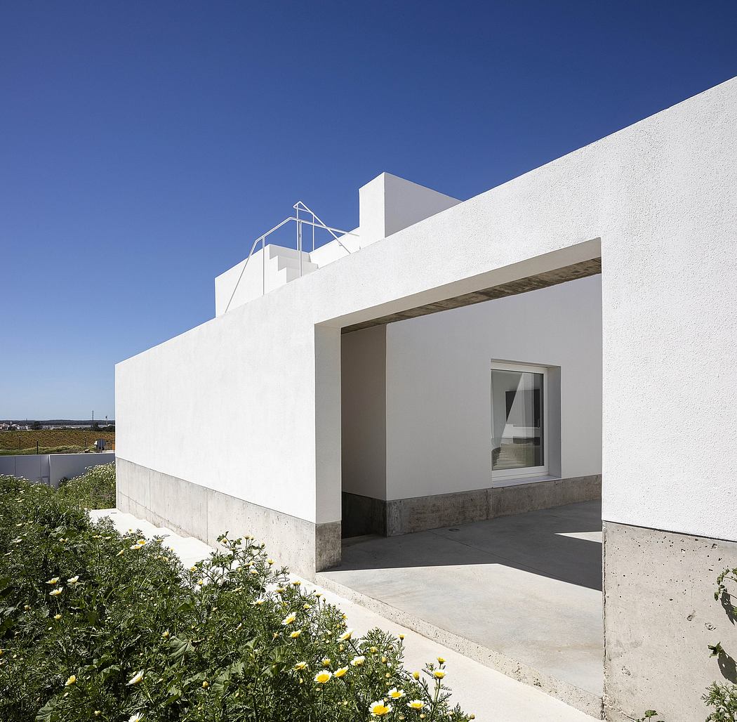 Minimalist white building with large window and flat roof against a blue sky.
