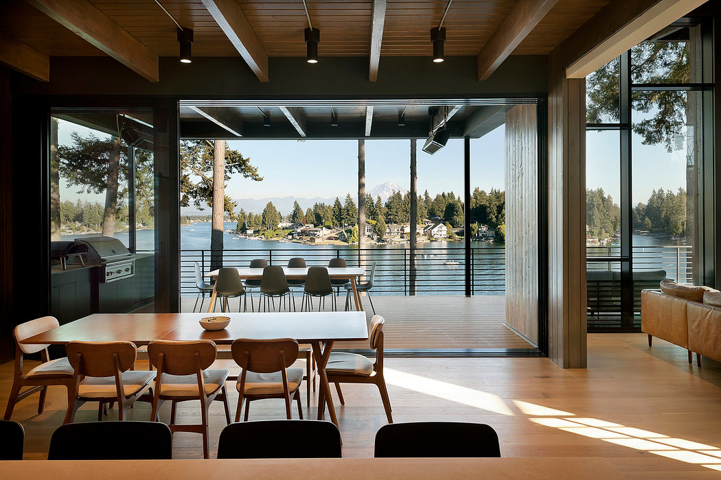 Modern dining room with large windows overlooking a lake.