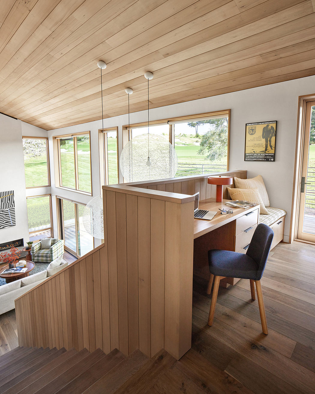 Cozy wooden interior with slanted ceiling, desk area, and large windows.
