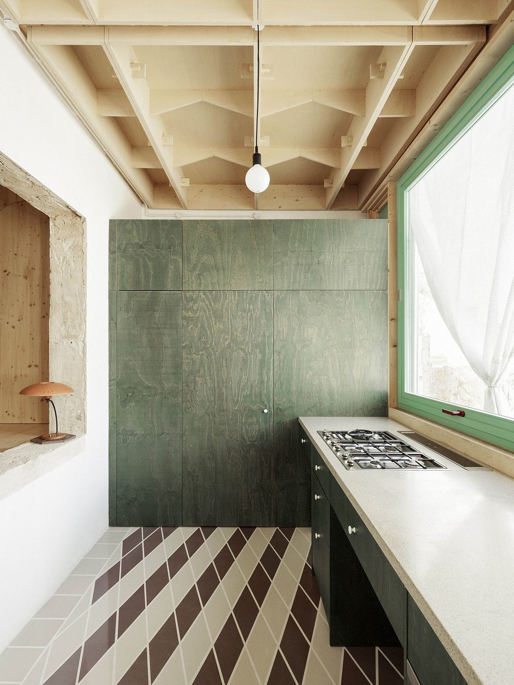 Modern kitchen corner with green cabinetry, patterned tiles, and exposed ceiling beams