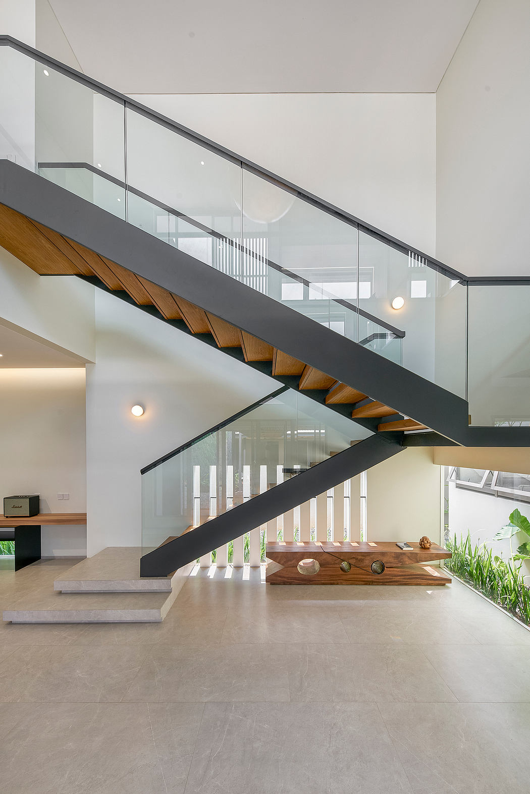 Modern staircase with glass railing inside a bright, minimalist interior.